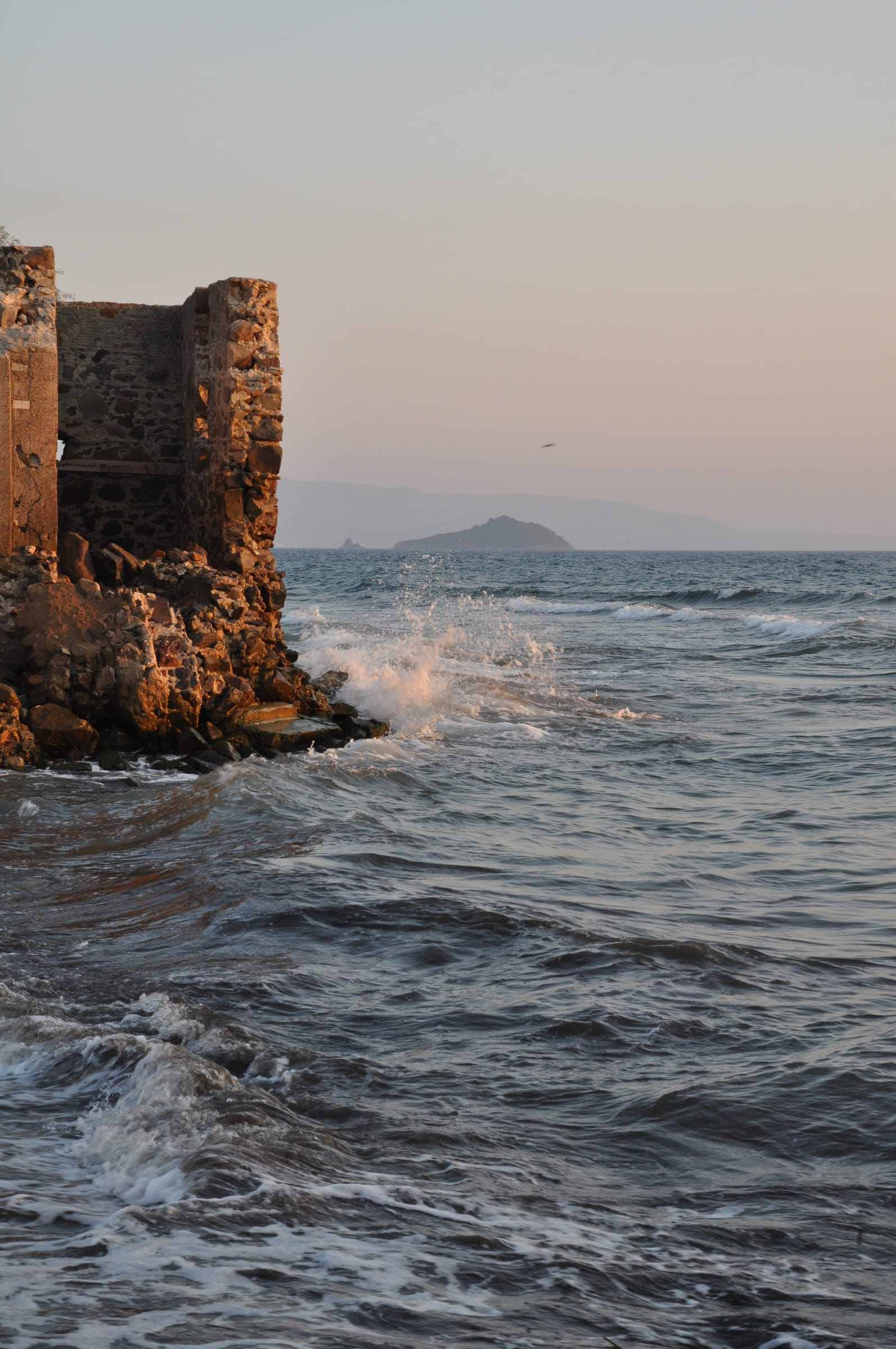 Waves meeting a rocky shore at sunset